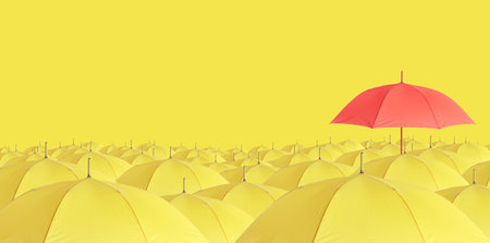 Red umbrella among yellow ones against color background. Banner designの写真素材