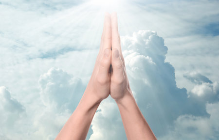 Woman praying against beautiful sky with sun, closeupの写真素材