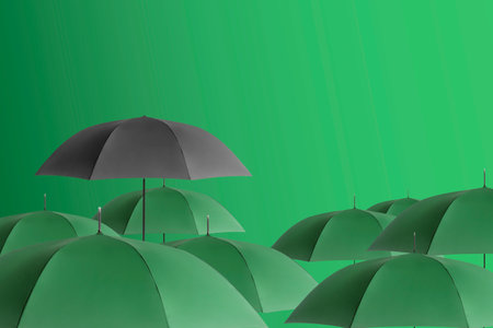Black umbrella among green ones against color backgroundの写真素材