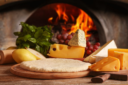 Fresh ingredients for pizza on wooden table against ovenの写真素材