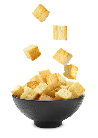 Delicious crispy croutons falling into bowl on white backgroundの写真素材