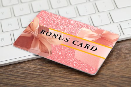 Bonus card with stylish design and computer keyboard on wooden tableの写真素材
