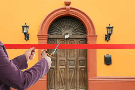 Woman cutting red ribbon at opening ceremony of house, closeupの写真素材