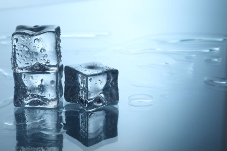 Cubes of clear ice on mirror surface, space for text