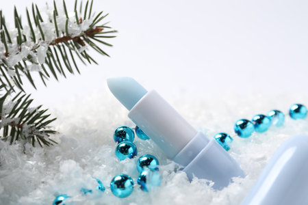 Moisturizing lip balm, Christmas decor and fir tree branches on artificial snow, closeup. Winter careの写真素材