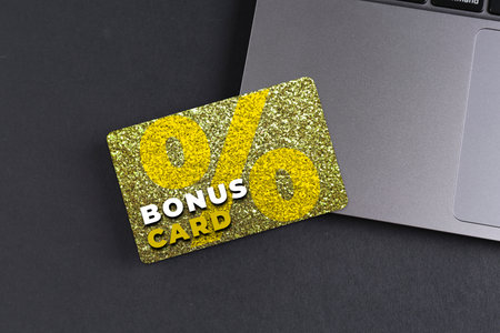 Bonus card with stylish design and laptop on grey tableの写真素材
