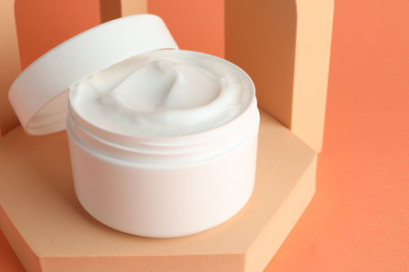 Stylish presentation of moisturizing body cream in jar on orange background, closeup. Space for textの写真素材