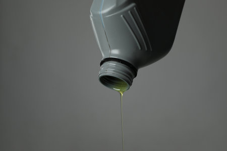 Pouring motor oil from canister on grey background, closeup. Space for textの写真素材
