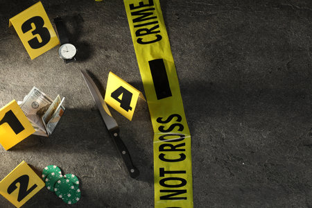 Forensic expert. Yellow crime scene tape, markers and evidences on grey table, above view. Space for textの写真素材