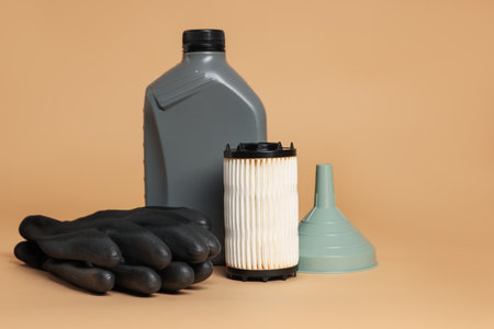 Motor oil in plastic canister, filter, gloves and funnel on beige backgroundの写真素材