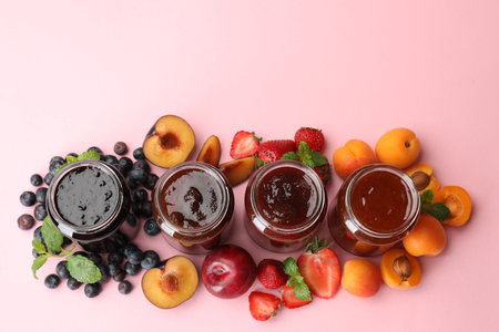 Different jams in jars and ingredients on light pink background, flat lay. Space for textの写真素材