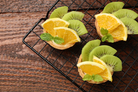 Tartlets with fruits and mint on wooden table, top view. Delicious dessertの写真素材
