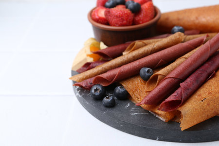 Fruit leather rolls and berries on white table, closeup. Space for textの写真素材