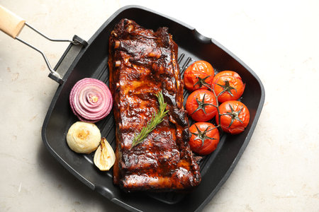 Delicious roasted pork ribs with rosemary, tomatoes and onions on light table, top viewの写真素材