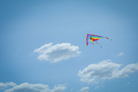 Colorful kite flying in blue sky, low angle view. Space for textの写真素材