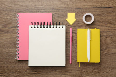 Notebooks, pens, sticky notes and decorative craft tape on wooden table, flat layの写真素材