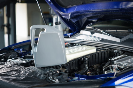 Canister of motor oil on car engine in workshop, closeup