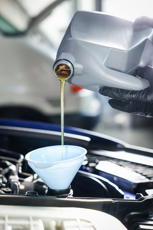 Worker pouring motor oil from canister into car engine, closeupの写真素材