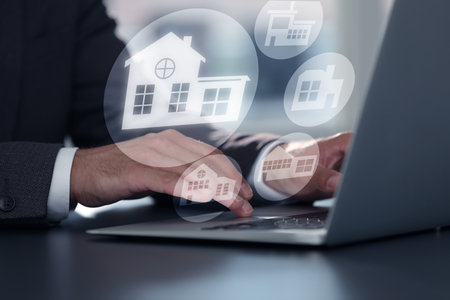 Real estate agent looking for housing via laptop at table, closeup. Illustrations of different buildings over deviceの写真素材
