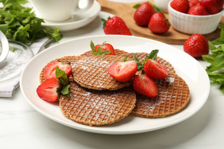 Tasty Dutch waffles (stroopwafels), mint and strawberries on white marble table, closeupの写真素材