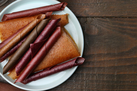 Tasty fruit leather rolls on wooden table, top view. Space for textの写真素材