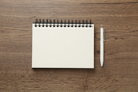 Notebook and pen on wooden table, flat lay