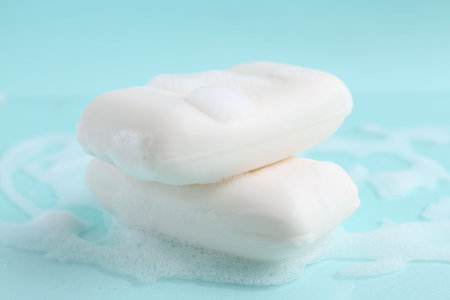 Soap bars with foam on light blue background, closeupの写真素材