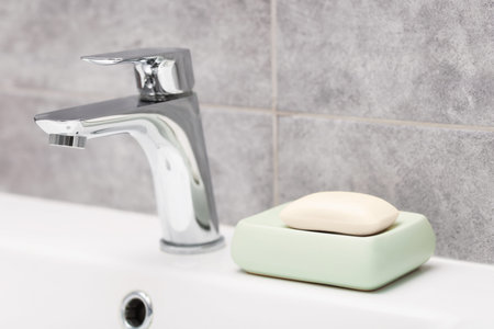 Soap bar near faucet on sink in bathroom, closeup