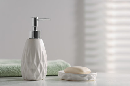 Soap bar, bottle of cosmetic product and towel on white table indoorsの写真素材