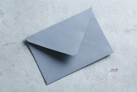 Beautiful invitation envelope on light gray table, top view