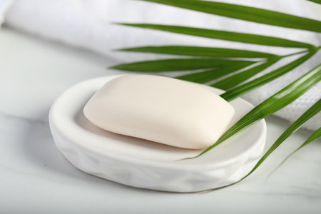 Soap bar, towel and palm leaf on white marble table, closeupの写真素材