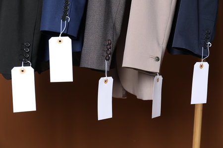 Different jackets with tags on brown background, closeupの写真素材