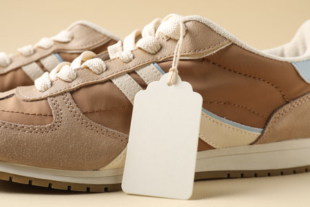 Pair of sneakers with tag on beige background, closeupの写真素材