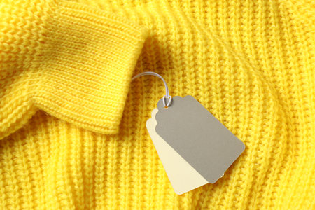 Cardboard tags on yellow knitted sweater, top viewの写真素材