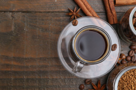 Cup of aromatic coffee, beans, instant powder and spices on wooden table, flat lay. Space for textの写真素材