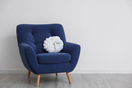 Comfortable blue armchair with cushion near white wall indoors, space for textの写真素材