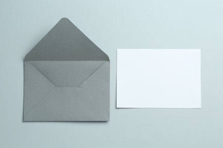 Blank invitation card and envelope on gray background, flat lay. Space for designの写真素材