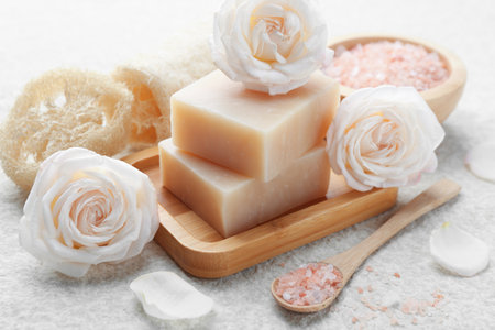 Soap bars, sea salt, loofah sponges and flowers on white textured table, closeupの写真素材