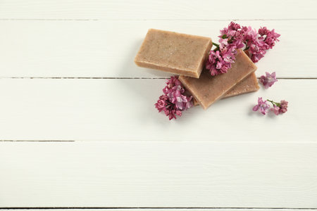 Soap bars and lilac flowers on white wooden table, flat lay. Space for textの写真素材
