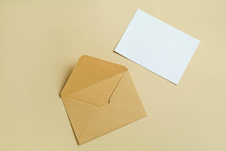 Blank invitation card and envelope on beige background, flat lay. Space for design