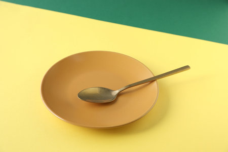 Plate and spoon on color background, closeupの写真素材