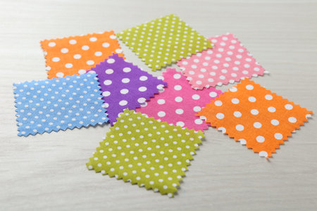 Samples of different fabrics on white wooden table, closeup