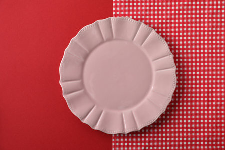 One empty plate and tablecloth on red background, top viewの写真素材