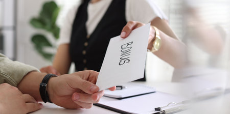 Boss giving envelope with word bonus to employee in office, closeupの写真素材