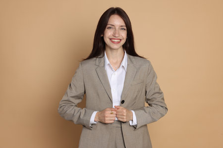 Happy woman in suit on beige backgroundの写真素材