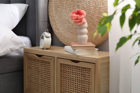 Bedside table with alarm clock, decor and books near bed indoorsの写真素材
