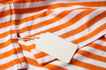 Cardboard tag on striped garment, closeup viewの写真素材