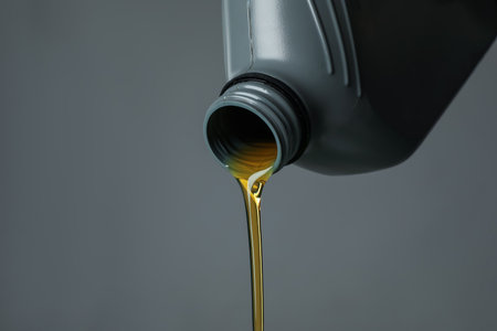 Pouring motor oil from canister on gray background, closeup. Space for textの写真素材