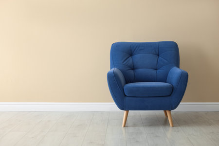 Comfortable soft blue armchair near beige wall indoors, space for textの写真素材