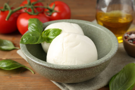Tasty mozzarella balls, tomatoes, oil and basil on wooden table, closeupの写真素材